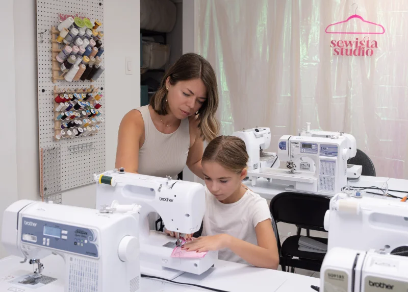 Instructor helping a child learn to use a sewing machine at summer camp