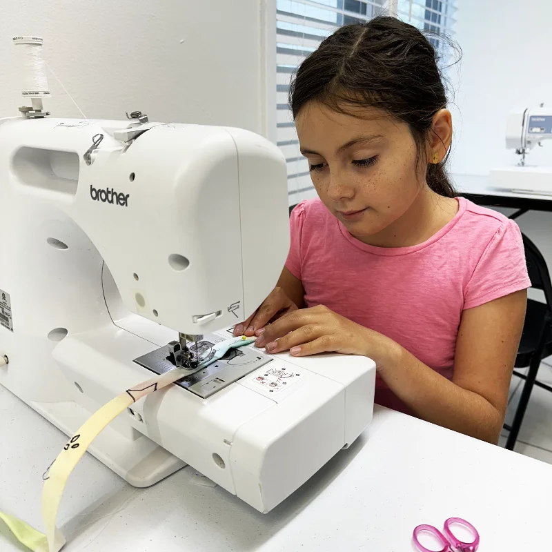 Girl operating a sewing machine at summer fashion camp for kids